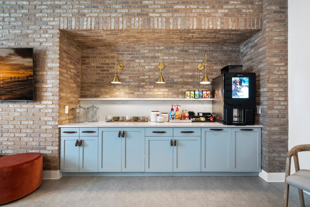 a small kitchen with blue cabinets and a brick wall