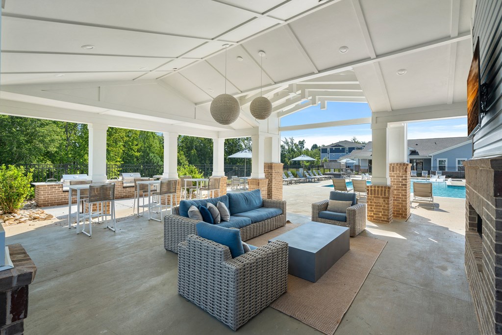 a covered patio with wicker furniture and a pool in the background