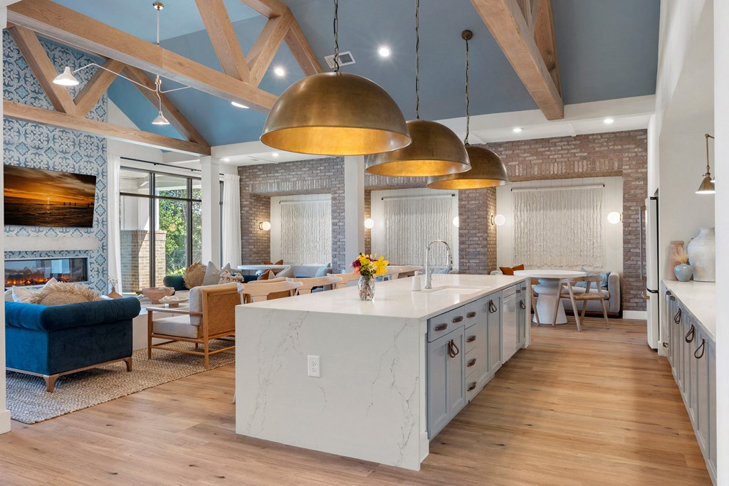 a kitchen with a large center island next to a living room with couches and a fireplace