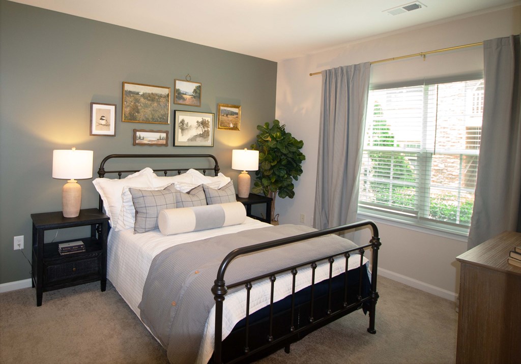 A bedroom with a large bed and a window with a view of trees.