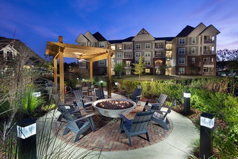 A patio with chairs and a fire pit in front of a building.