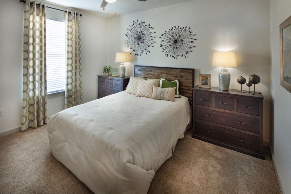 Vestavia Reserve Apartment with Wood Inspired flooring and washer and dryer sets in every home as well as an open layout bedroom with a large bed, a nightstand, and a dresser.
