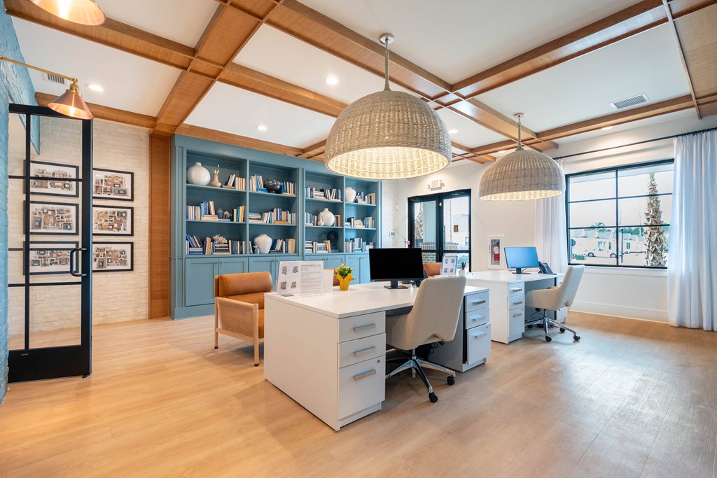 a home office with two desks and two chairs and a large window