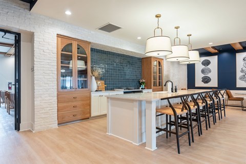 Amenities a large white kitchen with a long island and chairs
