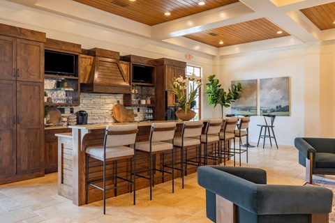 a kitchen with a long bar and chairs in front of it