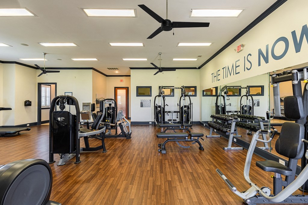 a gym with weights and cardio equipment and a sign that says the time is now