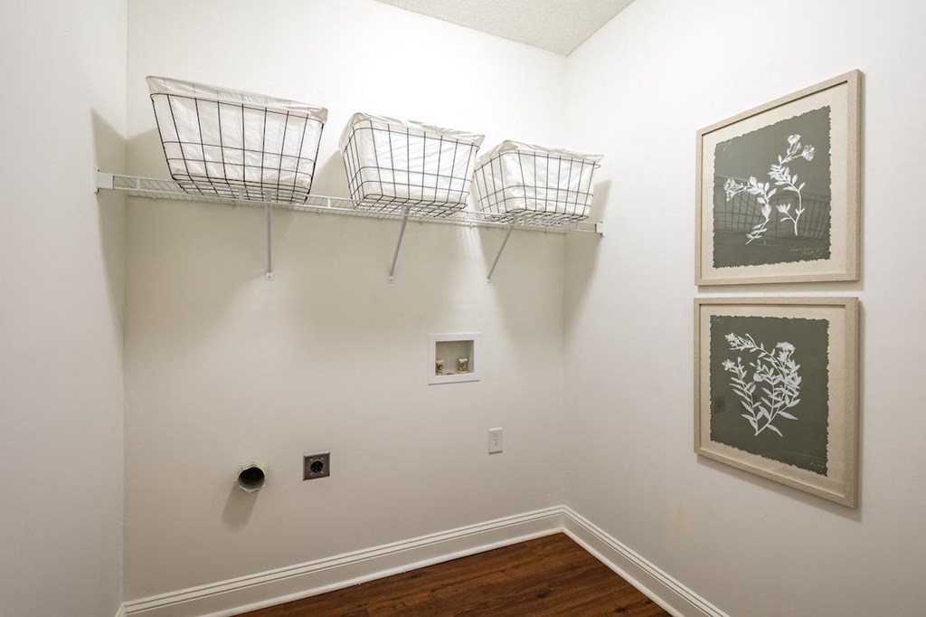 a white room with three wire baskets on the wall and pictures on the walls