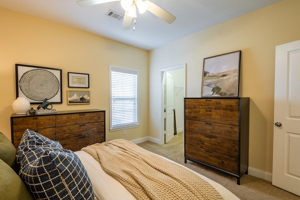 a bedroom with a bed and dresser and a ceiling fan