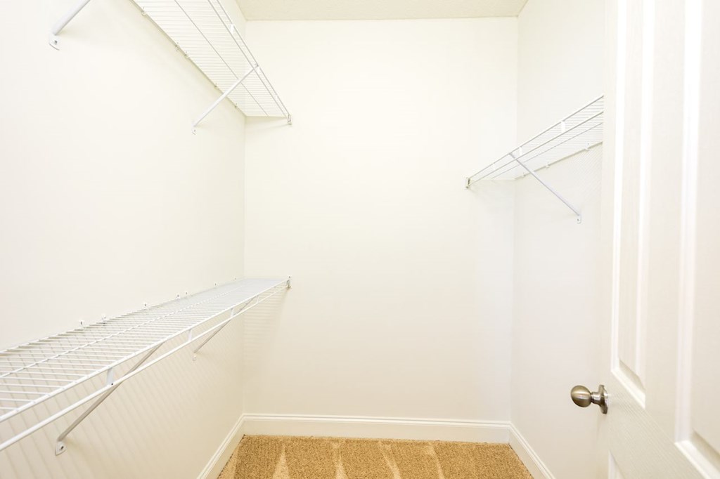 a walk in closet with two shelves and a door