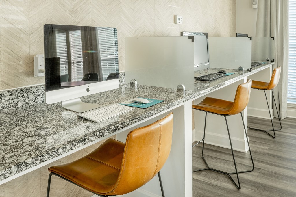 a kitchen with a counter with two chairs and a desk with a computer