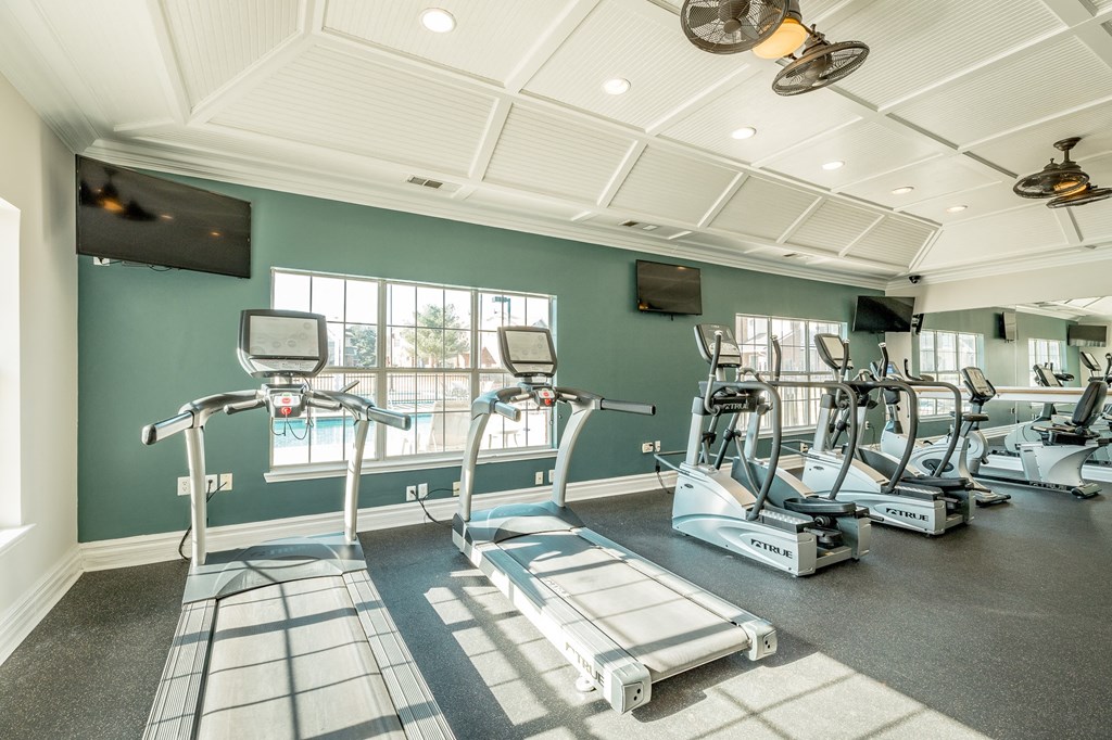 a gym with cardio machines and windows