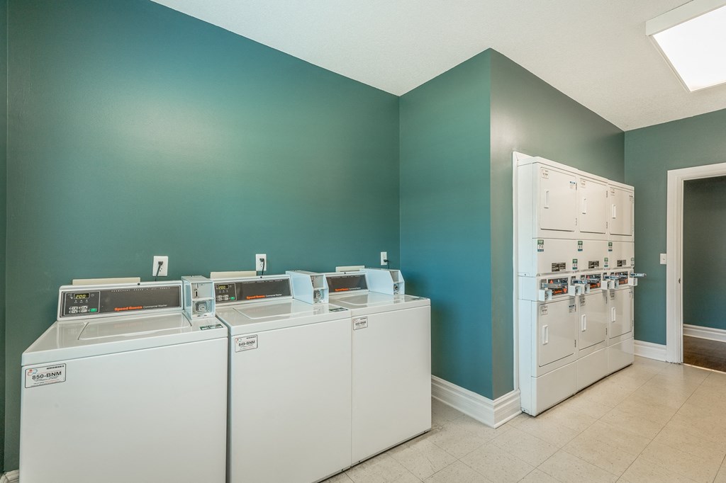 a laundry room with four washer and dryers and a door to a room