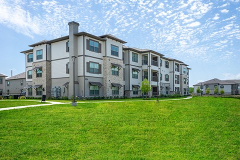 an apartment building with a green lawn in front of it
