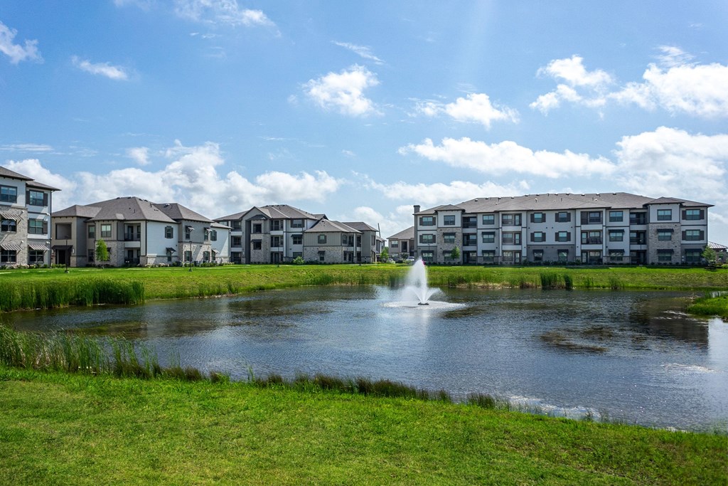 a pond with a fountain in front of some apartments