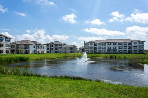 a pond with a fountain in front of some apartments