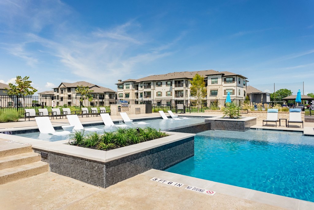 a swimming pool with white chairs and a building in the background