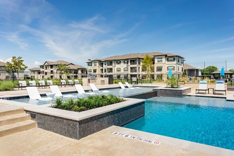 a swimming pool with white chairs and a building in the background
