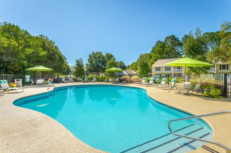 a swimming pool with chairs and umbrellas next to a building