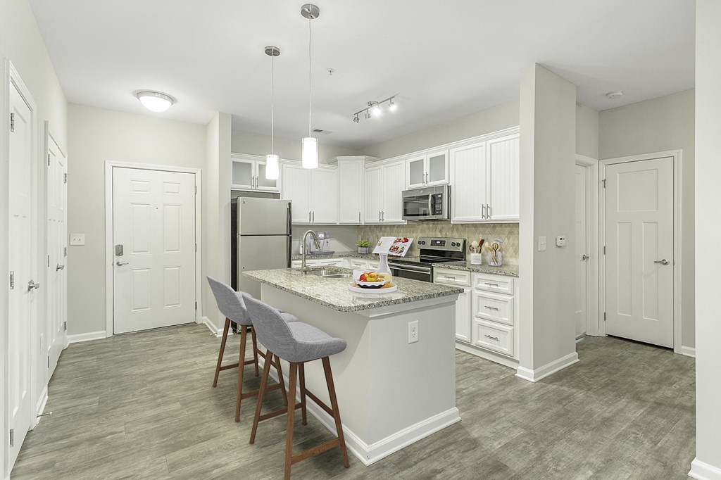 a kitchen with white cabinets and a marble counter top