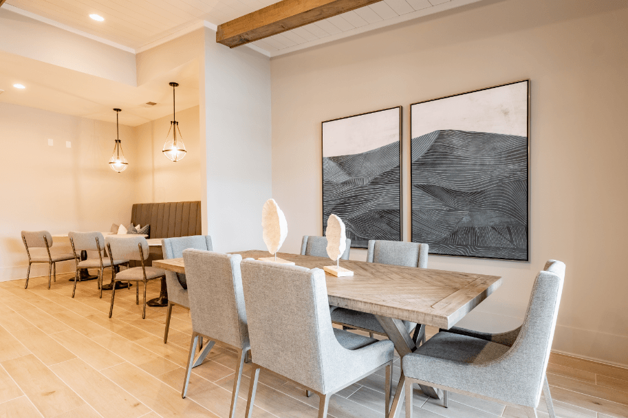 a dining room with a table and chairs and two paintings on the wall