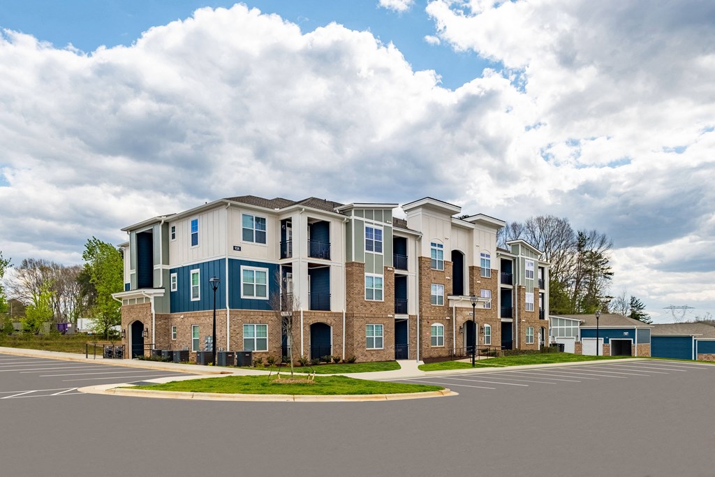 an apartment building with a parking lot and a cloudy sky