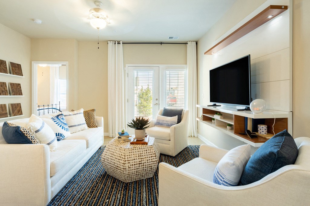 a living room with white furniture and a television