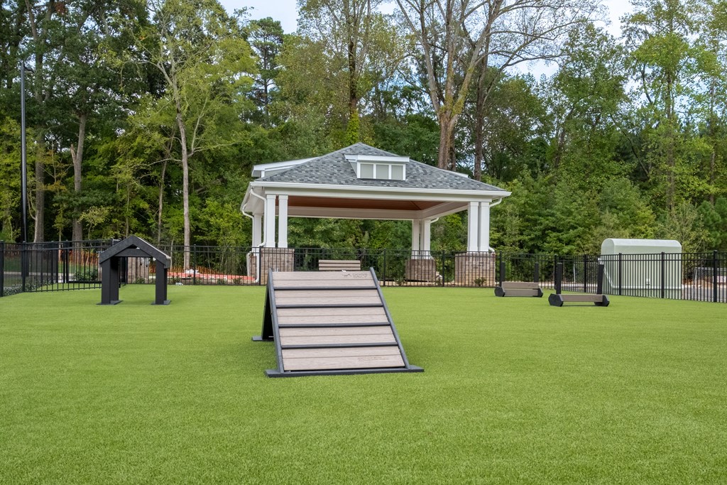 the gazebo and swing set on the lawn of a park