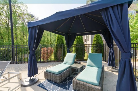 A blue canopy is over a patio with two chairs and a table at Hawthorne at the Hollow apartments in Soddy-Daisy, TN.