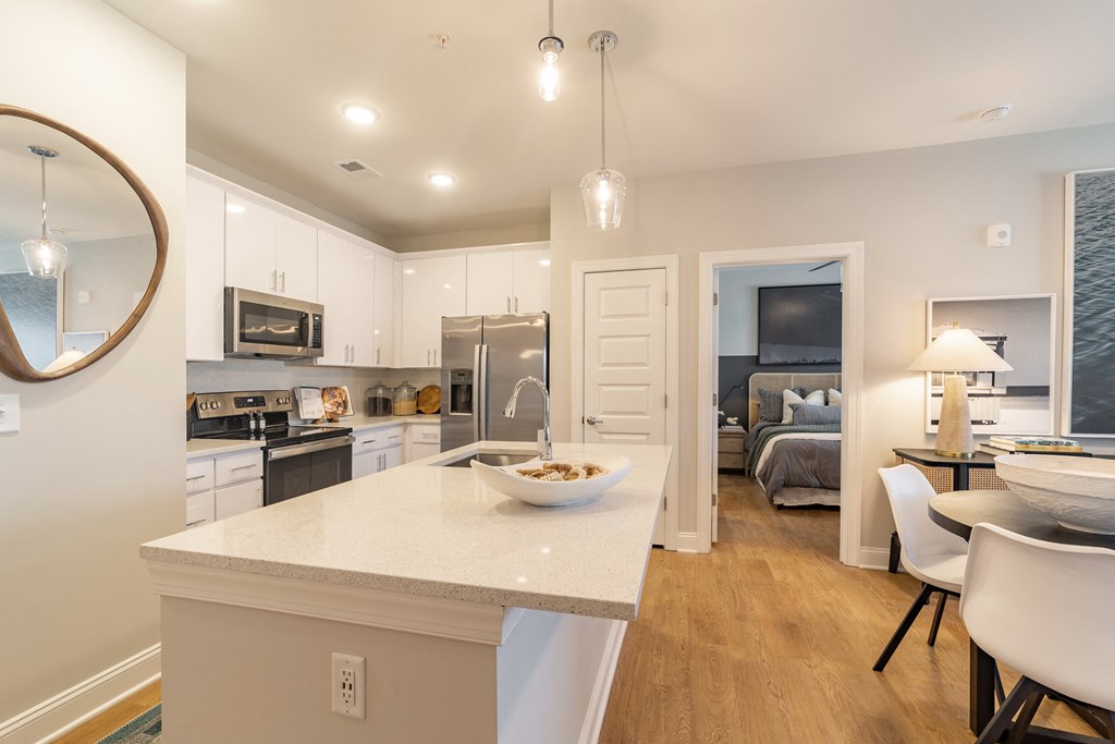 a white kitchen with a large island and a dining room