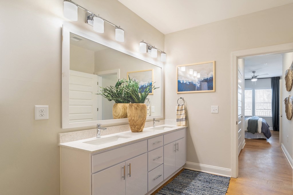 a bathroom with a sink and a mirror and a door to a bedroom