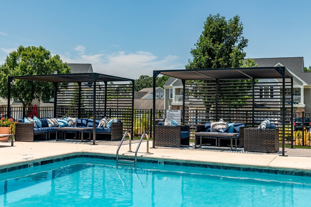a swimming pool with lounge chairs and umbrellas next to a resort style pool
