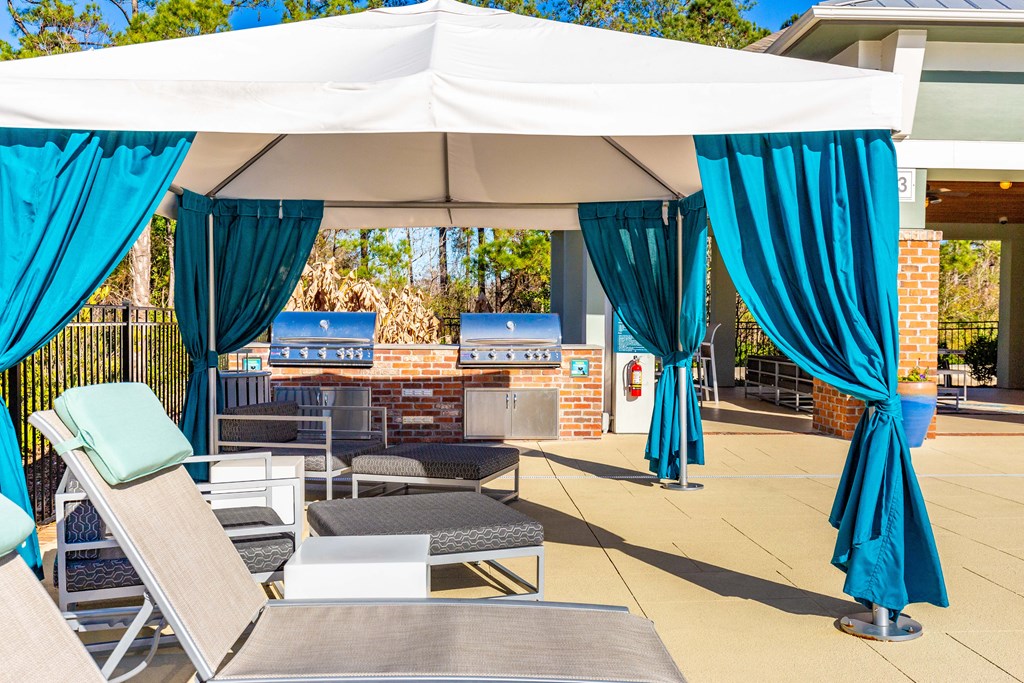 a patio with blue curtains and chairs and a white tent