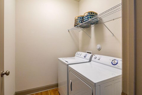 a washer and dryer in a laundry room with a shelf on the wall