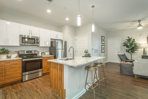 an open kitchen and living room with a marble counter top