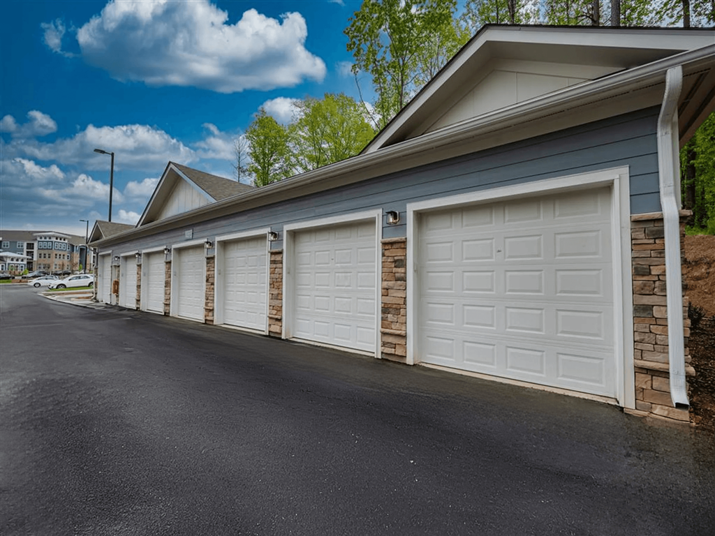 A row of white garage doors in front of a blue house.