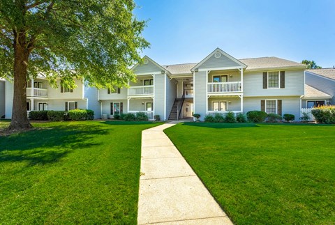 A row of white houses with green lawns in front.