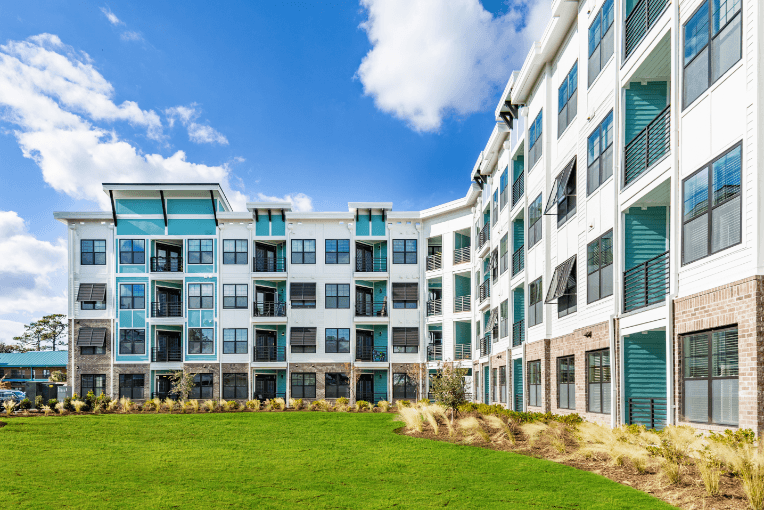 a large apartment building with green windows and a green lawn