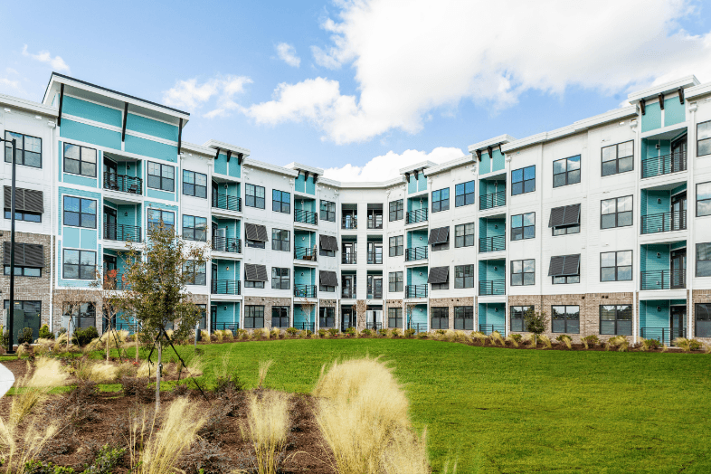 an exterior view of an apartment building with a green lawn