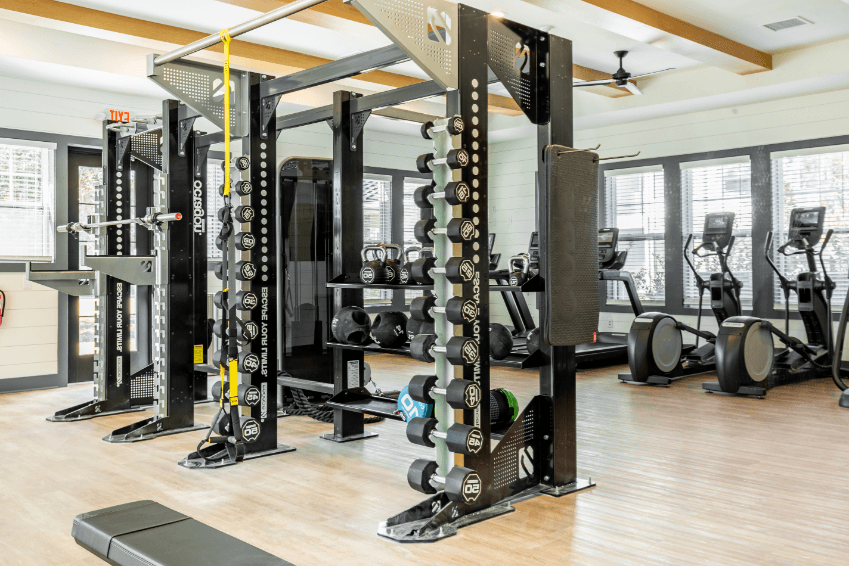 a gym with weights and cardio equipment on the floor and windows