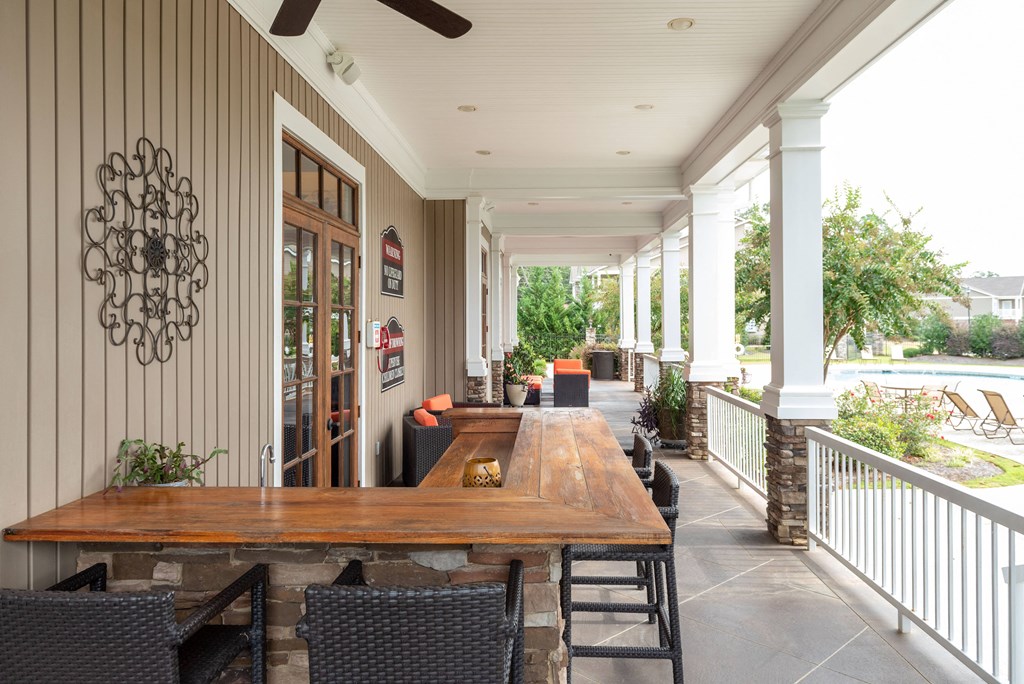a long porch with a long wooden table and chairs