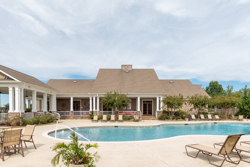a swimming pool with chairs and a house in the background