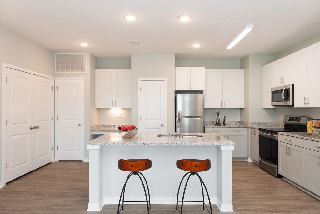 a kitchen with white cabinets and a large island with two stools