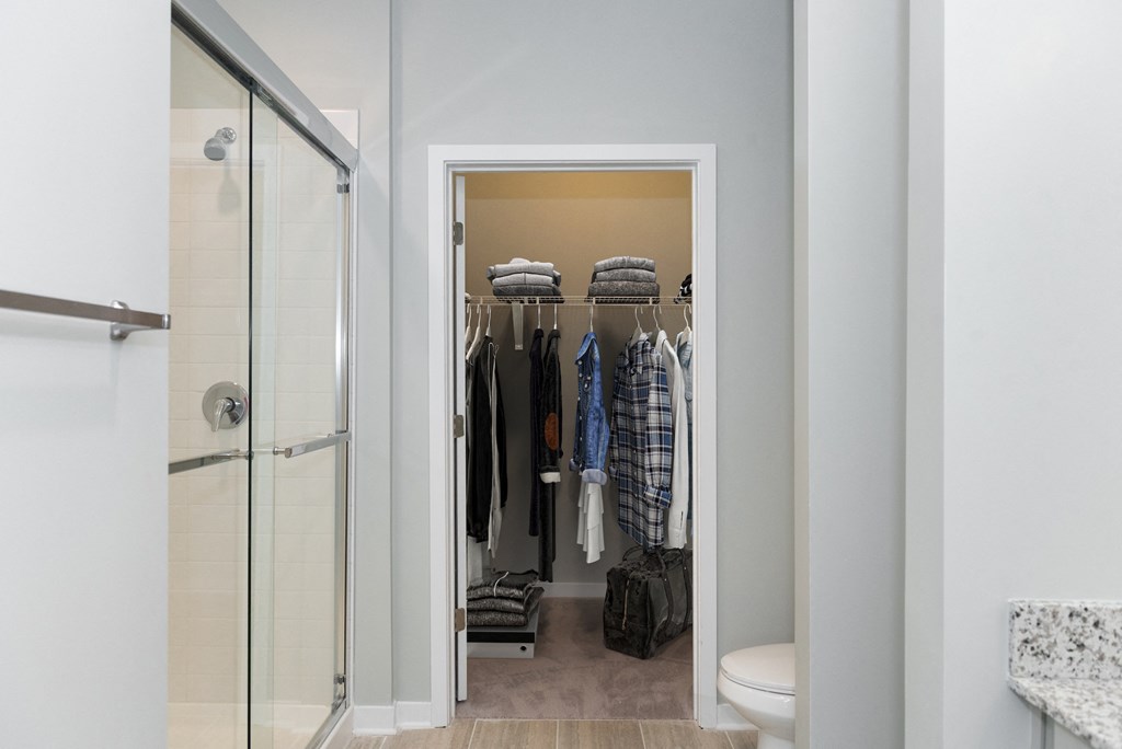 a walk in closet in a 555 waverly unit with a glass shower