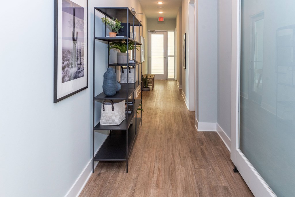 a long hallway with a bookshelf and a window in the end of it