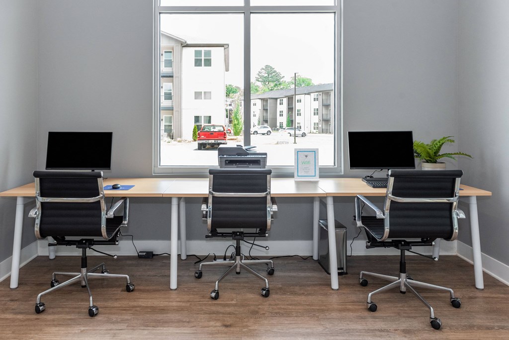 an empty office with three desks and chairs and a window