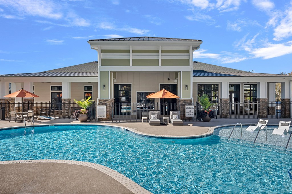 Outdoor Swimming Pool with Loungers Surrounding and Umbrellas Open.