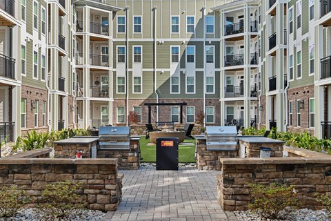 A courtyard surrounded by buildings with a stone wall and grills in the center.