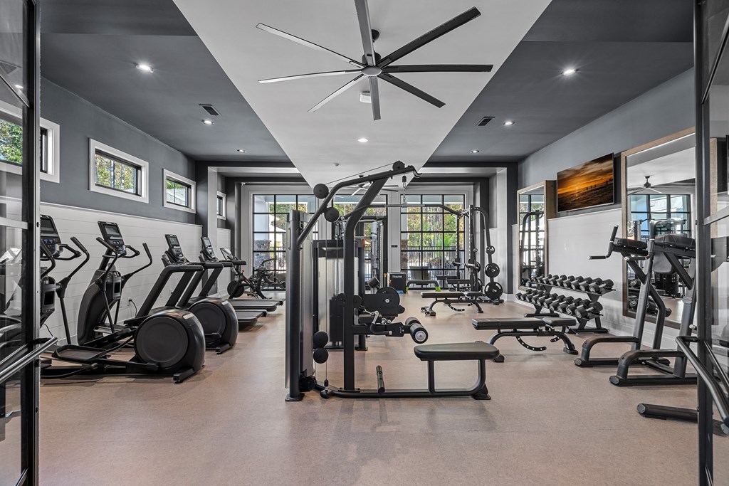 A spacious gym with a variety of equipment and a ceiling fan.