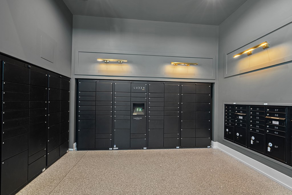A room with a wall of black lockers and a counter with a digital display.
