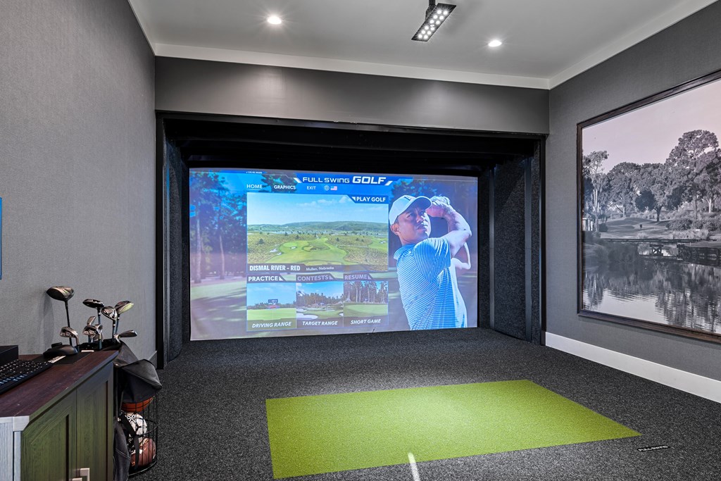 Golf Simulator with large screen and putting green on the ground.